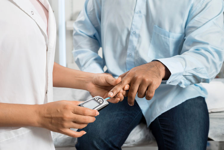 Doctor performing a finger-prick blood glucose test on a patient