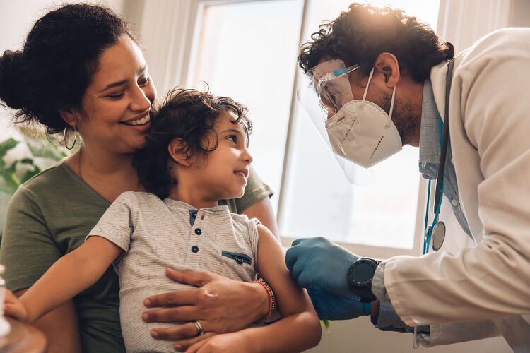 Doctor giving a vaccination to a young boy held by his mother