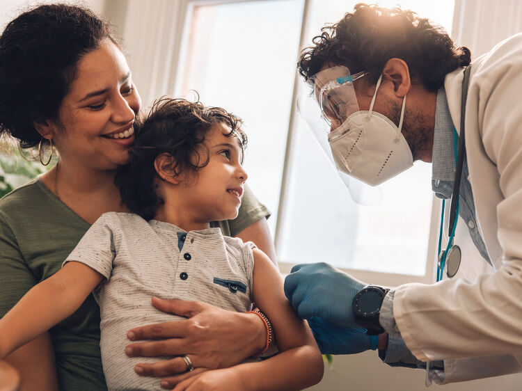 Doctor giving a vaccination to a young boy held by his mother