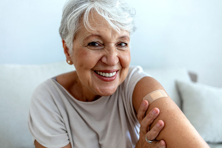 Smiling older woman with a plaster on her arm after a vaccination