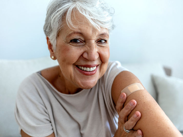 Smiling older woman with a plaster on her arm after a vaccination